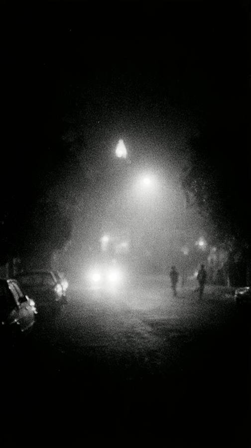 Une rue la nuit dans la brume, deux lampadaires allumés