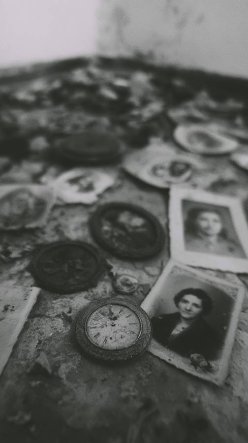 Des portraits et une montre posés sur une table poussiéreuse