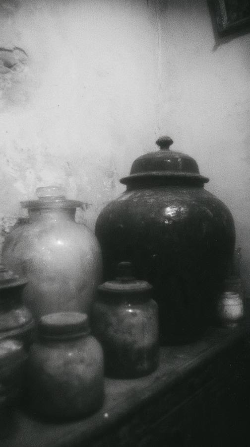 Des pots et des urnes sur une étagère, un mur taché
