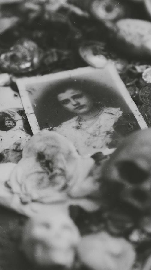 Un portrait de femme posé sur un tas d'objets, avec un crâne