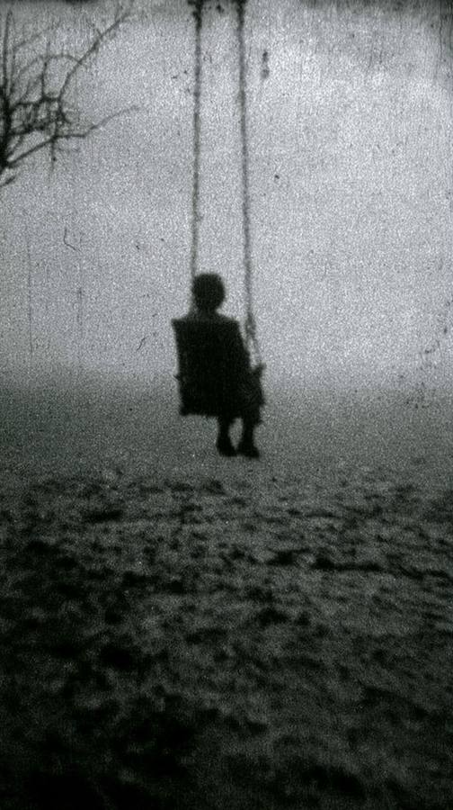 Une balançoire dans la brume, une silhouette assise dessus