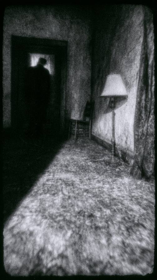 Un couloir sombre, une lampe allumée, une porte ouverte