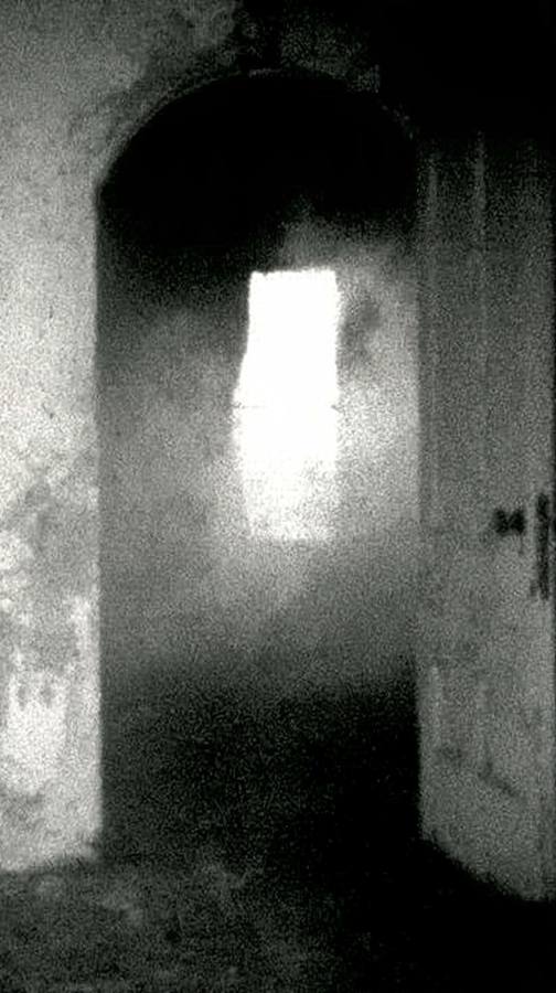 Une arche sombre ouvrant sur une porte éclairée